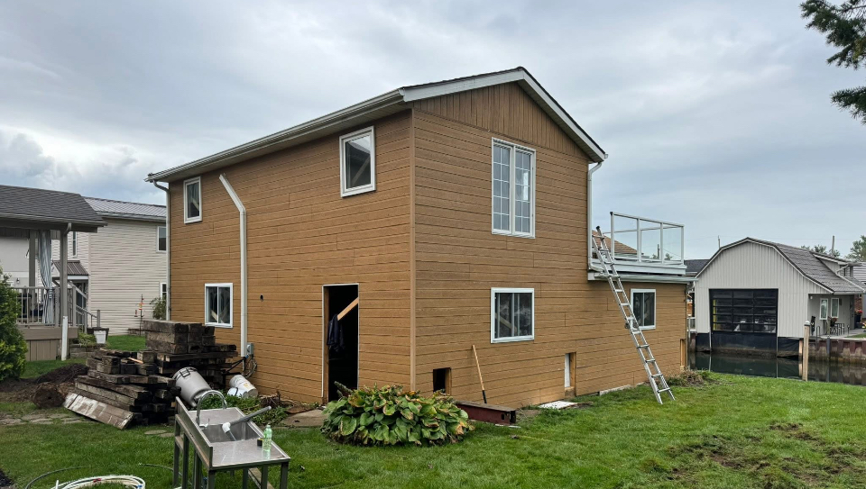 Two-storey home re-clad in engineered wood siding with new windows by Kuiper Construction